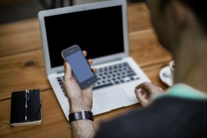 man using phone and laptop for meeting