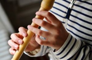 person playing the recorder in striped sweater