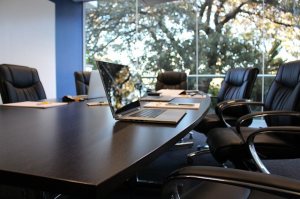 Empty conference meeting room by an open window with an apple macbook on the table.