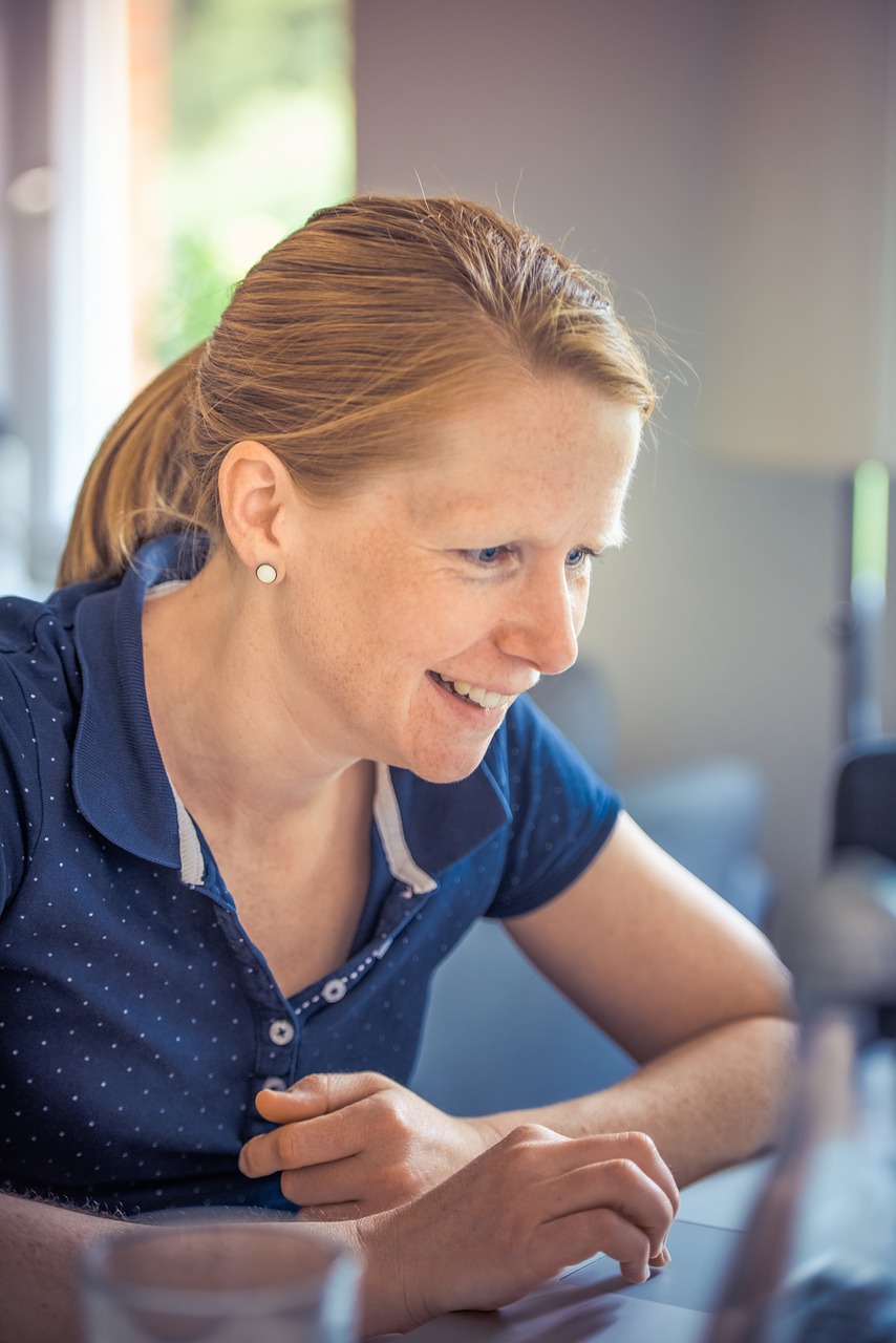 vrouw die lacht naar haar laptop terwijl ze FreeConference.com gebruikt voor het delen van schermen