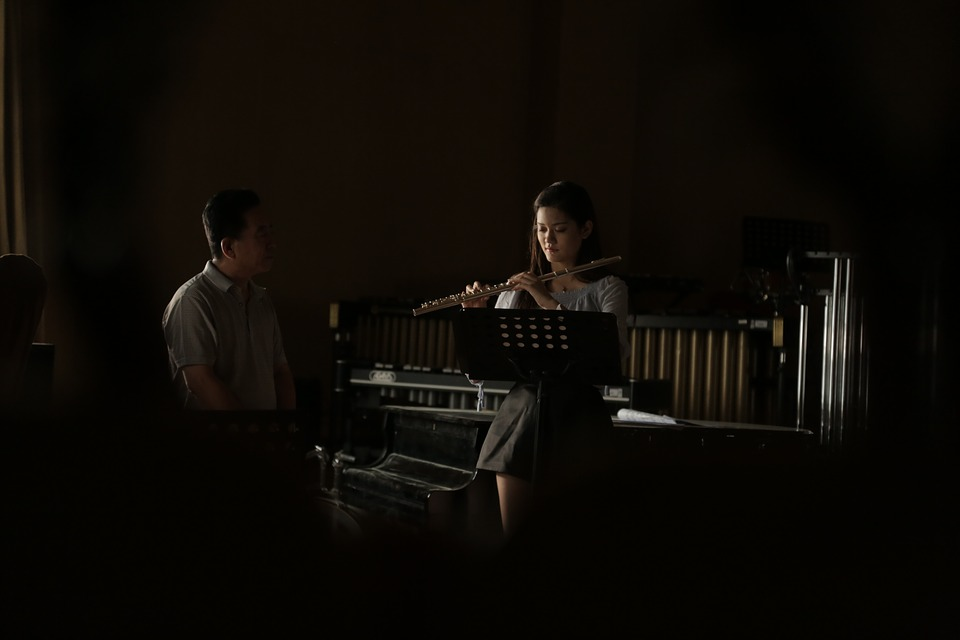 man tutoring one oh his music students in a dark music room