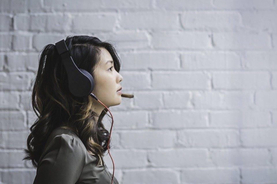 woman wearing conference call headset in front of white brick wall
