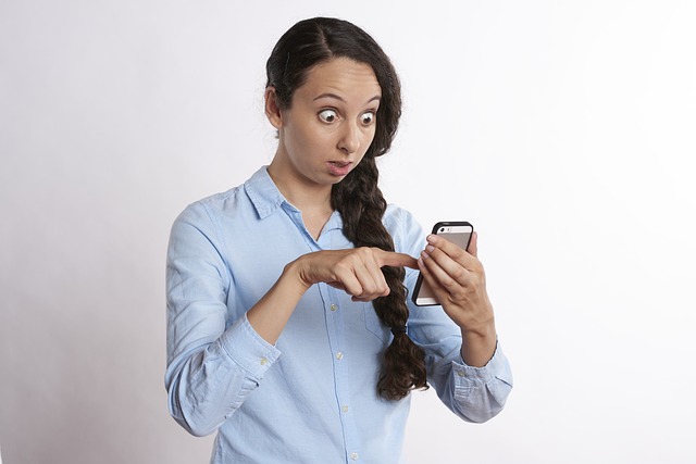 Women looking shocked at her smartphone feeling conference call anxiety