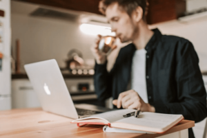 young man looking at the laptop and drinking coffee