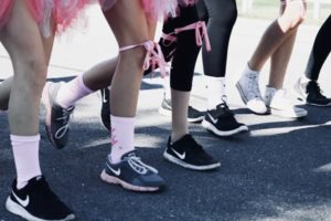 View of six lower bodies lined up in a runner’s stance ready to start a run for charity