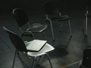 Black and white view of chairs aligned in a circle with a tablet laid down on chair in foreground.jpg